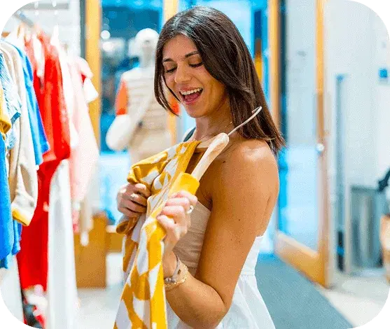 Pessoa sorrindo escolhendo uma roupa em uma loja